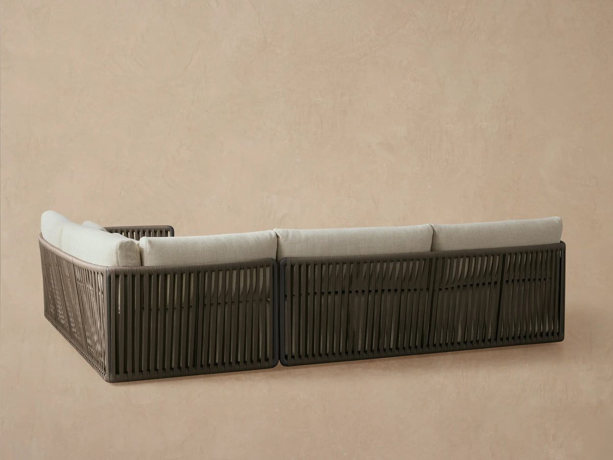 Close-up of Lisbon Outdoor Two-Piece Sectional's dark brown woven rope backrest and charcoal frame, with light beige cushions.