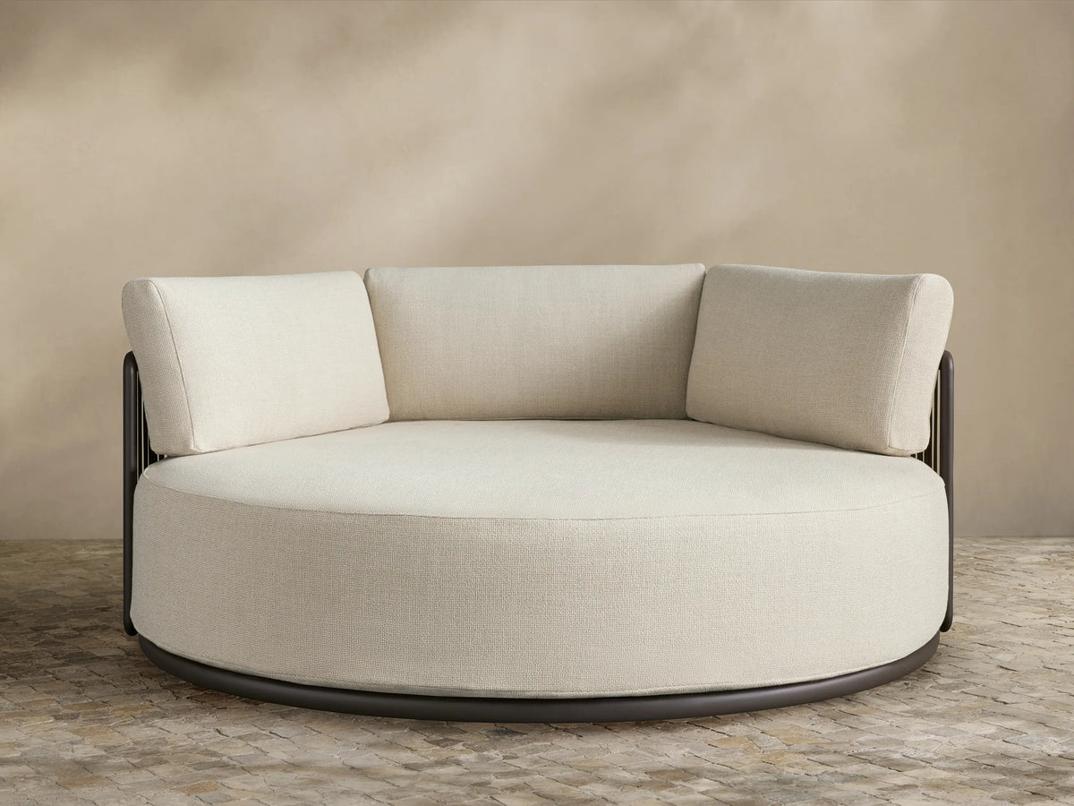 Lisbon Outdoor Daybed: round, cream performance fabric seat & three back cushions on a dark aluminum frame.