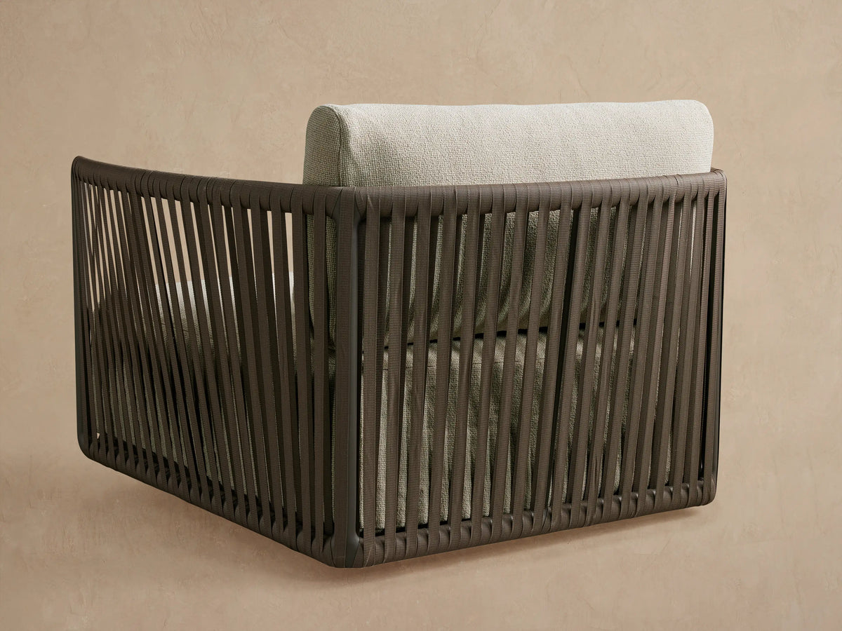 Angled close-up of Lisbon Outdoor Swivel Chair. Dark brown rope frame, light textured natural fabric cushions, back and lumbar pillows.