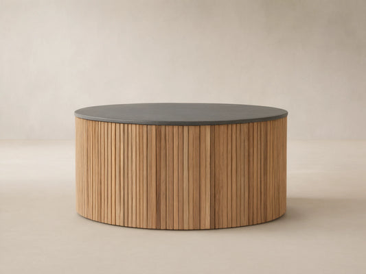 Pompeii Outdoor Round Coffee Table featuring a dark gray concrete top and cylindrical base of vertical reclaimed teak slats, on stone patio.