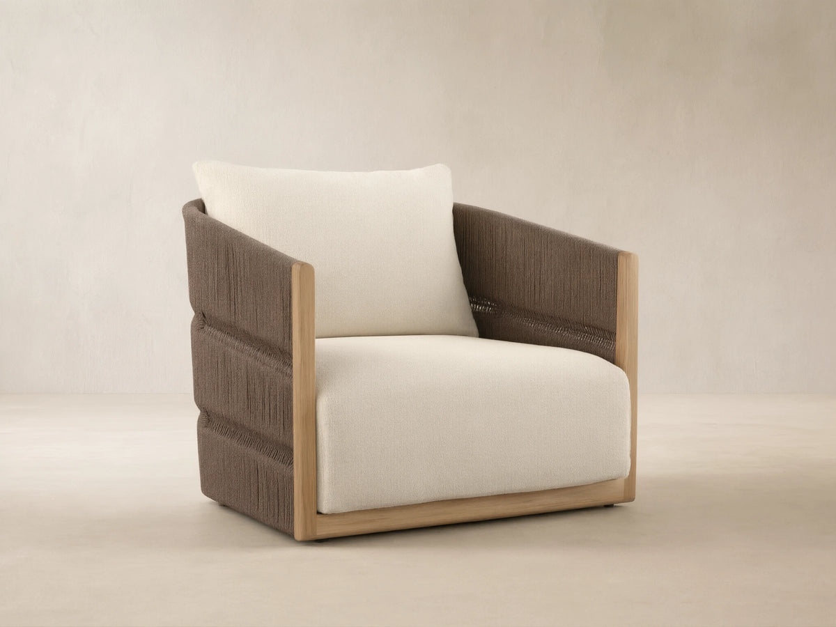 Manadala Outdoor Swivel Chair with natural teak frame, dark brown woven rope arms/back, ivory cushions, on patio tiles.