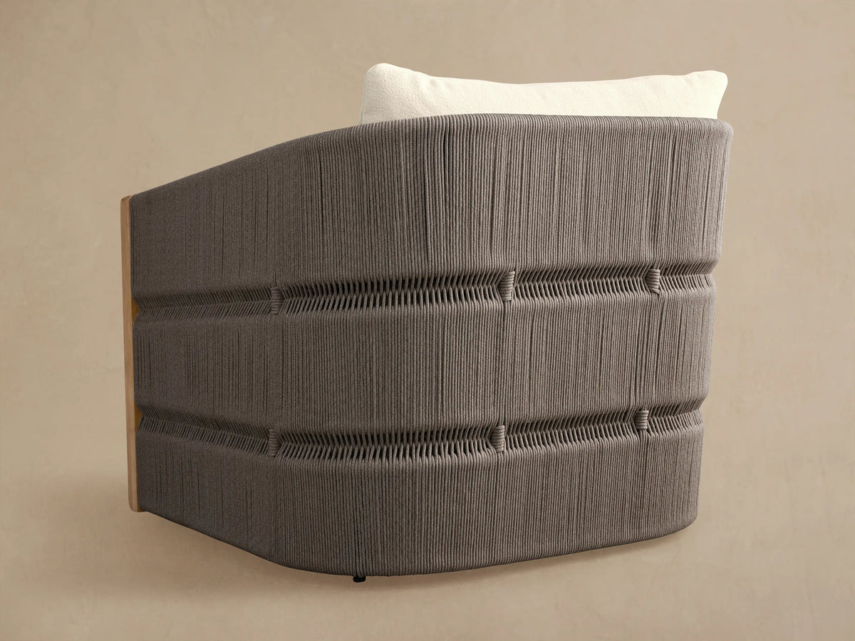 Rear view of Manadala Outdoor Swivel Chair. Curved gray handwoven rope back, natural teak side, white cushion.