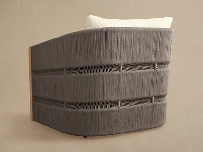 Rear view of Manadala Outdoor Swivel Chair. Curved gray handwoven rope back, natural teak side, white cushion.