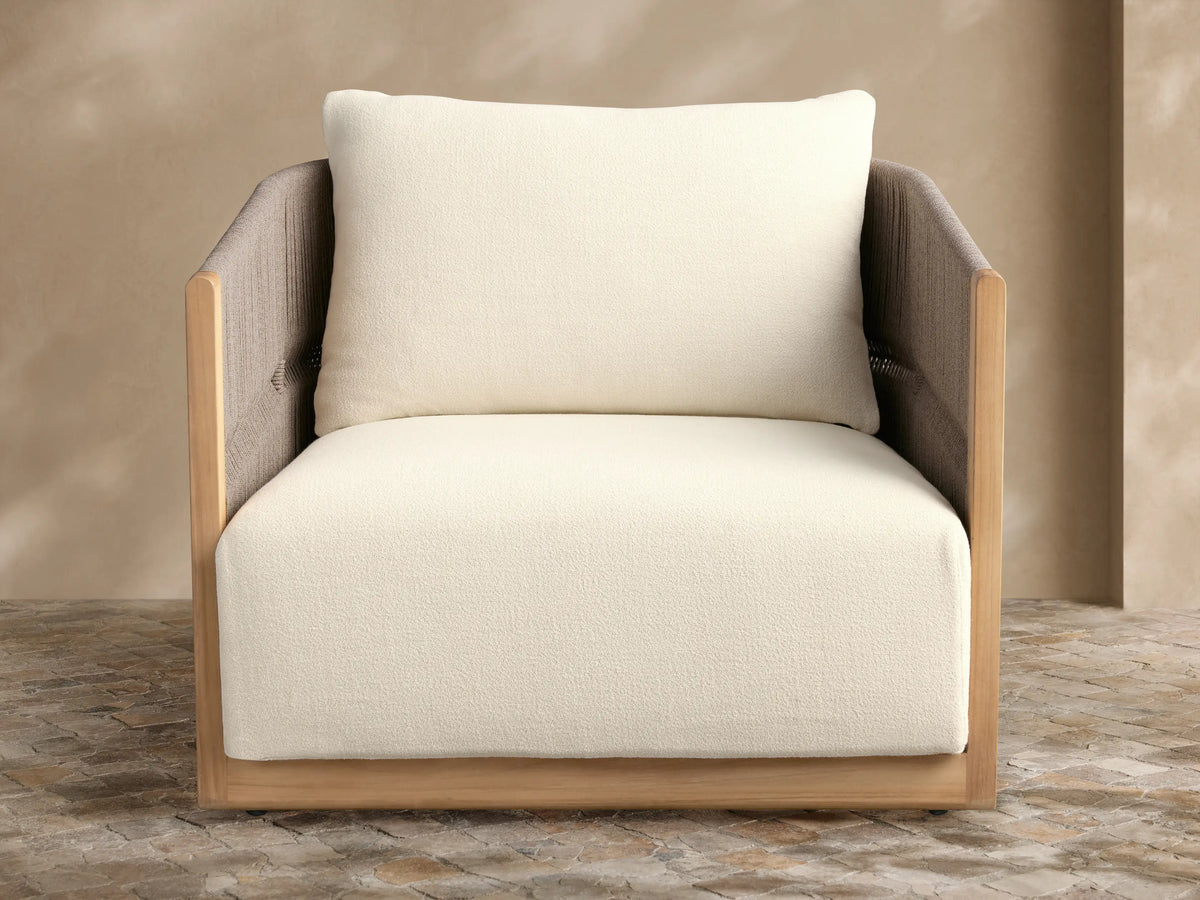 Manadala Outdoor Swivel Chair, natural teak frame, grey woven arms/back, plush ivory cushions, on a stone patio.