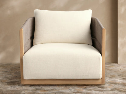 Manadala Outdoor Swivel Chair, natural teak frame, grey woven arms/back, plush ivory cushions, on a stone patio.