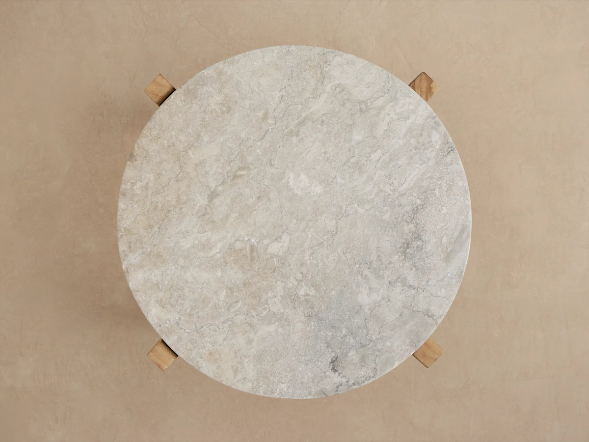 Mari Outdoor End Table, angled view. Round, veined grey marble top on sturdy light brown teak wood legs.