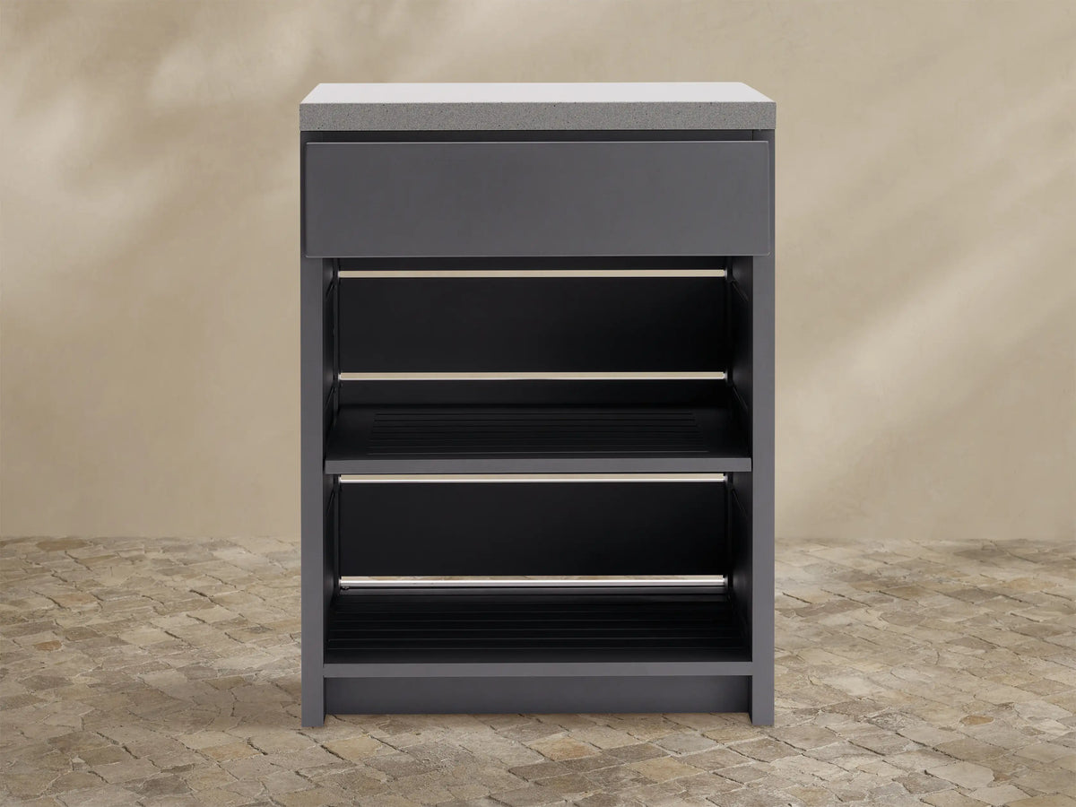 Dark gray outdoor aluminum modular kitchen cabinet with light gray sintered stone top, single drawer, and two slatted shelves.