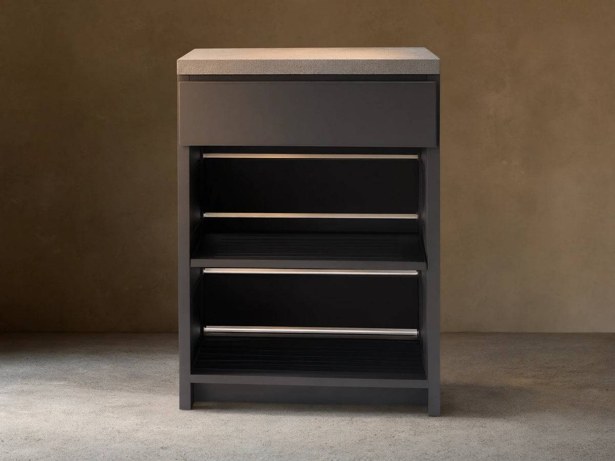 Dark gray outdoor aluminum modular kitchen cabinet with light gray sintered stone top, single drawer, and two slatted shelves.