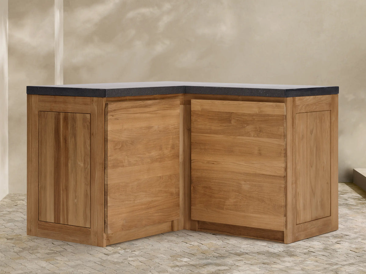 Modular kitchen corner cabinet made of natural teak wood with a dark gray sintered stone countertop, on a tiled floor.