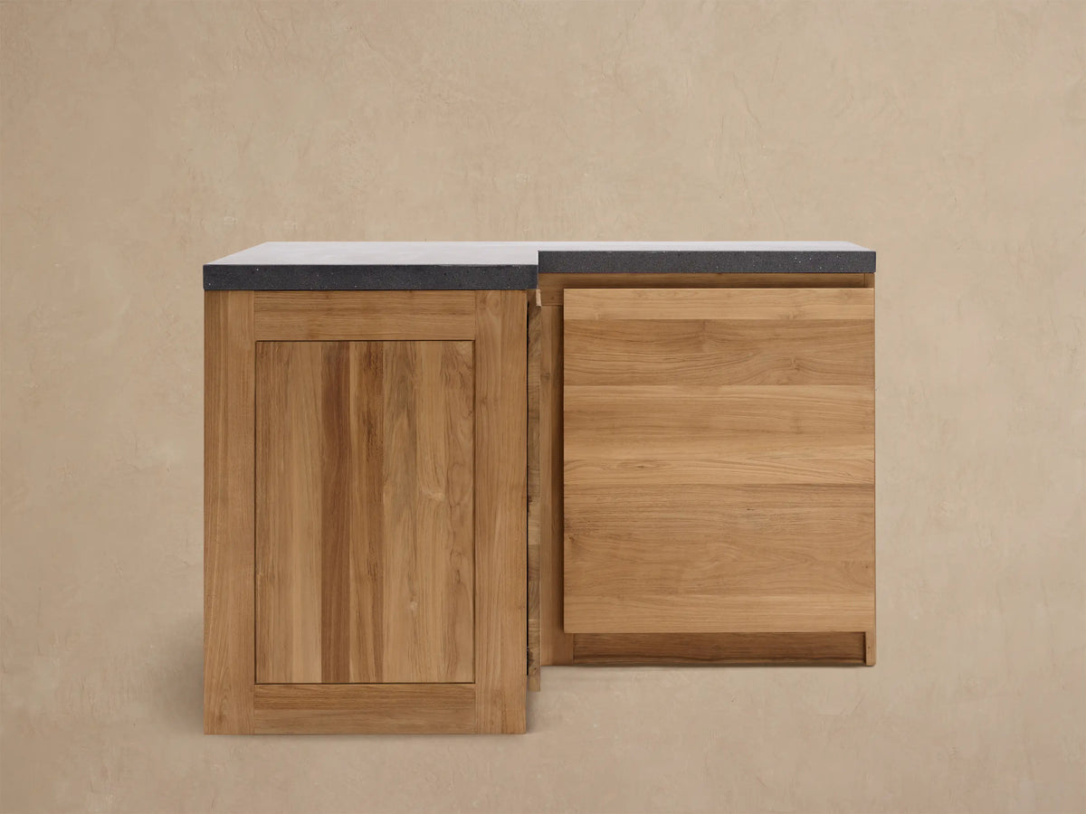 Modular kitchen corner cabinet made of natural teak wood with a dark gray sintered stone countertop, on a tiled floor.