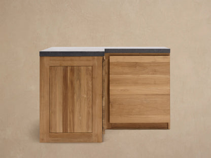 Modular kitchen corner cabinet made of natural teak wood with a dark gray sintered stone countertop, on a tiled floor.