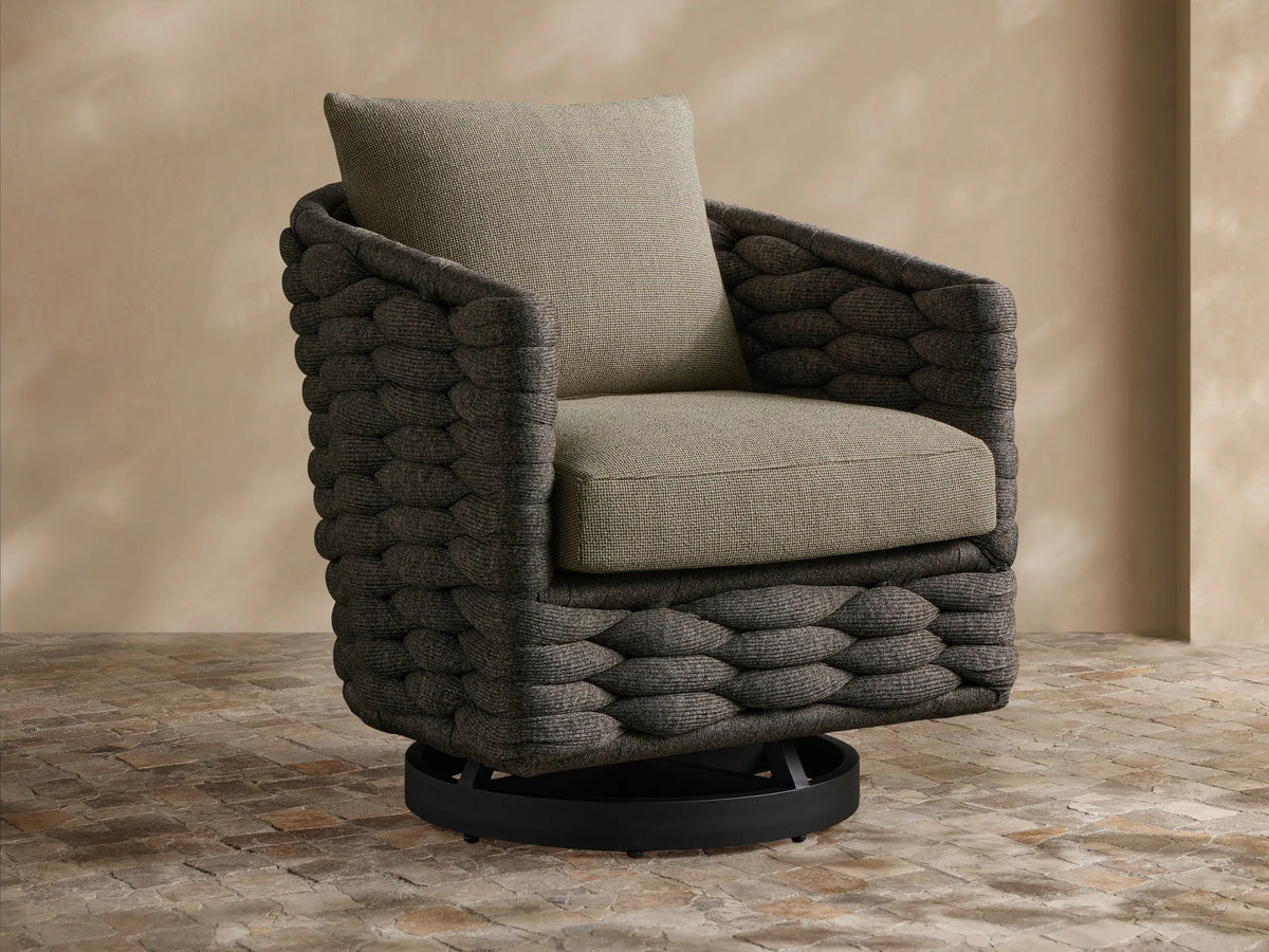 Melbourne Outdoor Swivel Chair: dark charcoal woven body, light olive-gray cushions. Slight angle, on a stone patio.
