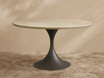 Outdoor round dining table with light beige textured stone top & dark gray flared pedestal Launette base on a tiled patio.