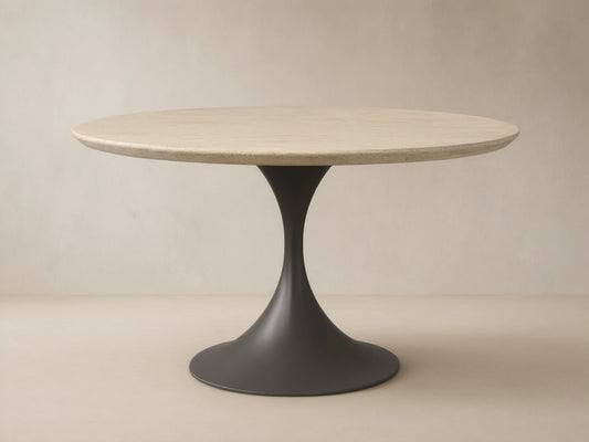 Outdoor round dining table with light beige textured stone top & dark gray flared pedestal Launette base on a tiled patio.