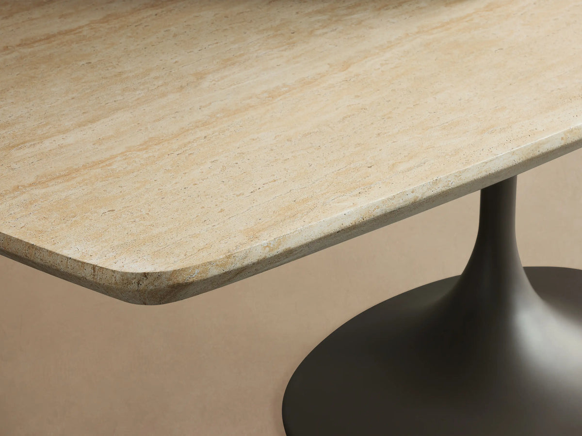 Outdoor Dining Table with light oval top on dark gray Launette tulip base, centered on patterned patio with beige wall and shadows.
