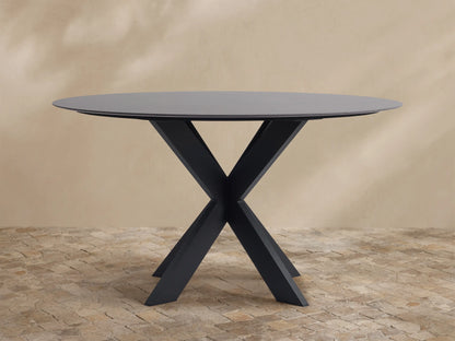 Round dark grey outdoor dining table with a black X-shaped Apex base on a light brown tiled patio.