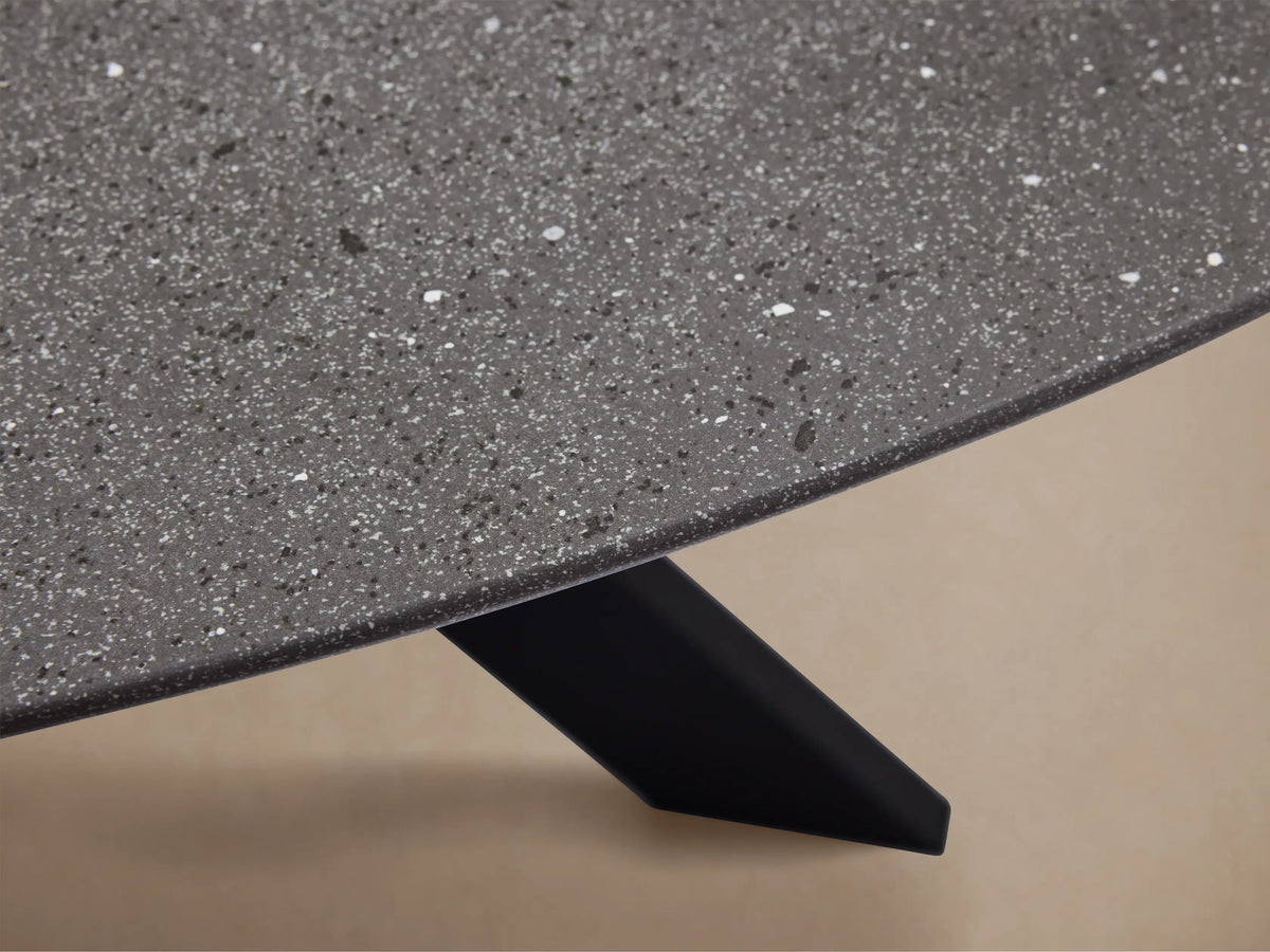 Round dark grey outdoor dining table with a black X-shaped Apex base on a light brown tiled patio.