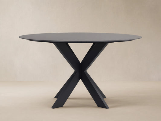 Round dark grey outdoor dining table with a black X-shaped Apex base on a light brown tiled patio.
