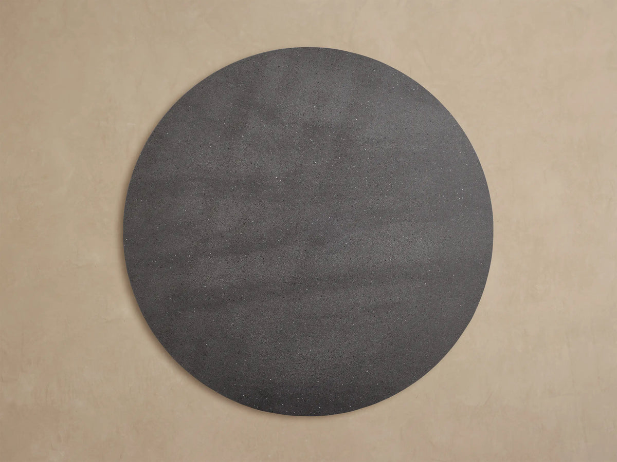 Close-up of the Outdoor Round Dining Table's dark gray speckled surface and black angular apex base.