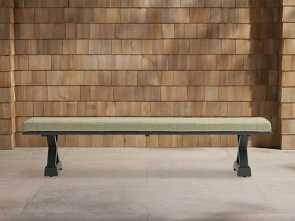 Montego Outdoor Aluminum Dining Bench with dark frame and Eden Sage cushion, against a wooden wall on a patio.