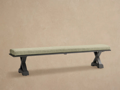 Montego Outdoor Aluminum Dining Bench with dark frame and Eden Sage cushion, against a wooden wall on a patio.