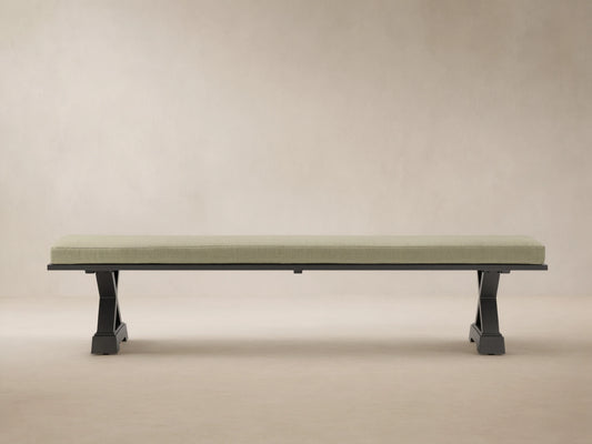 Montego Outdoor Aluminum Dining Bench with dark frame and Eden Sage cushion, against a wooden wall on a patio.