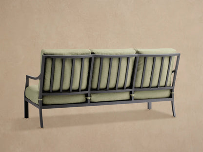 Angled close-up of Montego Outdoor Aluminum Sofa in Eden Sage. Dark gray frame with slatted back, light green cushions.