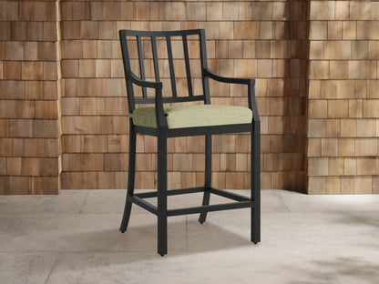 Montego Outdoor Aluminum Counter Stool, dark gray, with slatted back, armrests & light green Eden Sage cushion on a patio.