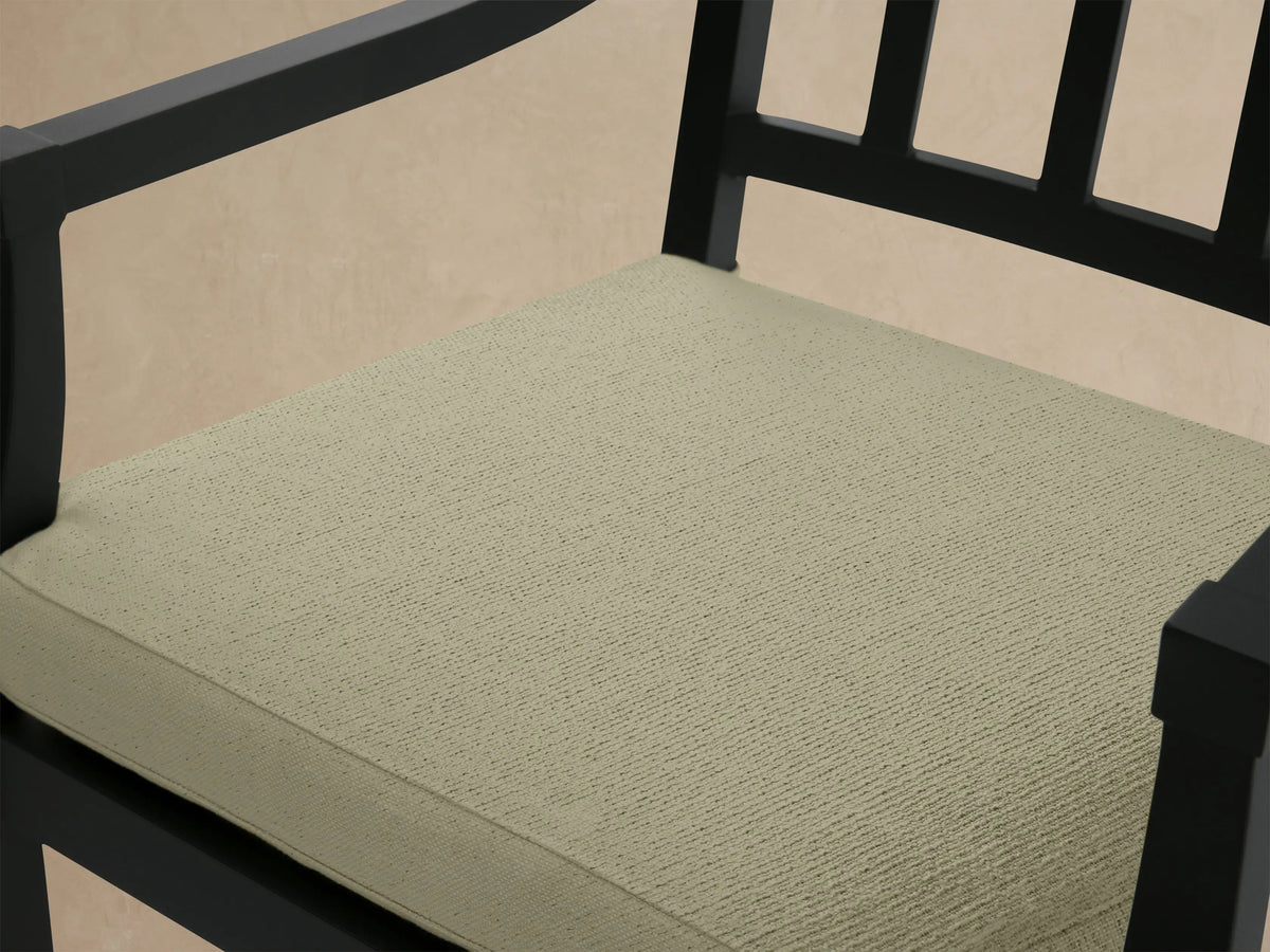 Montego Outdoor Aluminum Counter Stool with dark frame, slatted back, armrests, & light green Eden Sage cushion on patio.