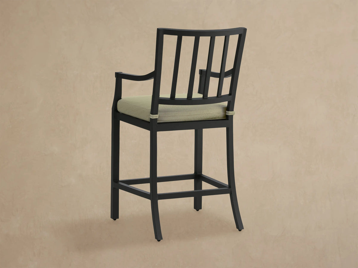 Close-up of Montego Outdoor Aluminum Counter Stool, showing its black aluminum frame with slatted back and textured Eden Sage cushion.