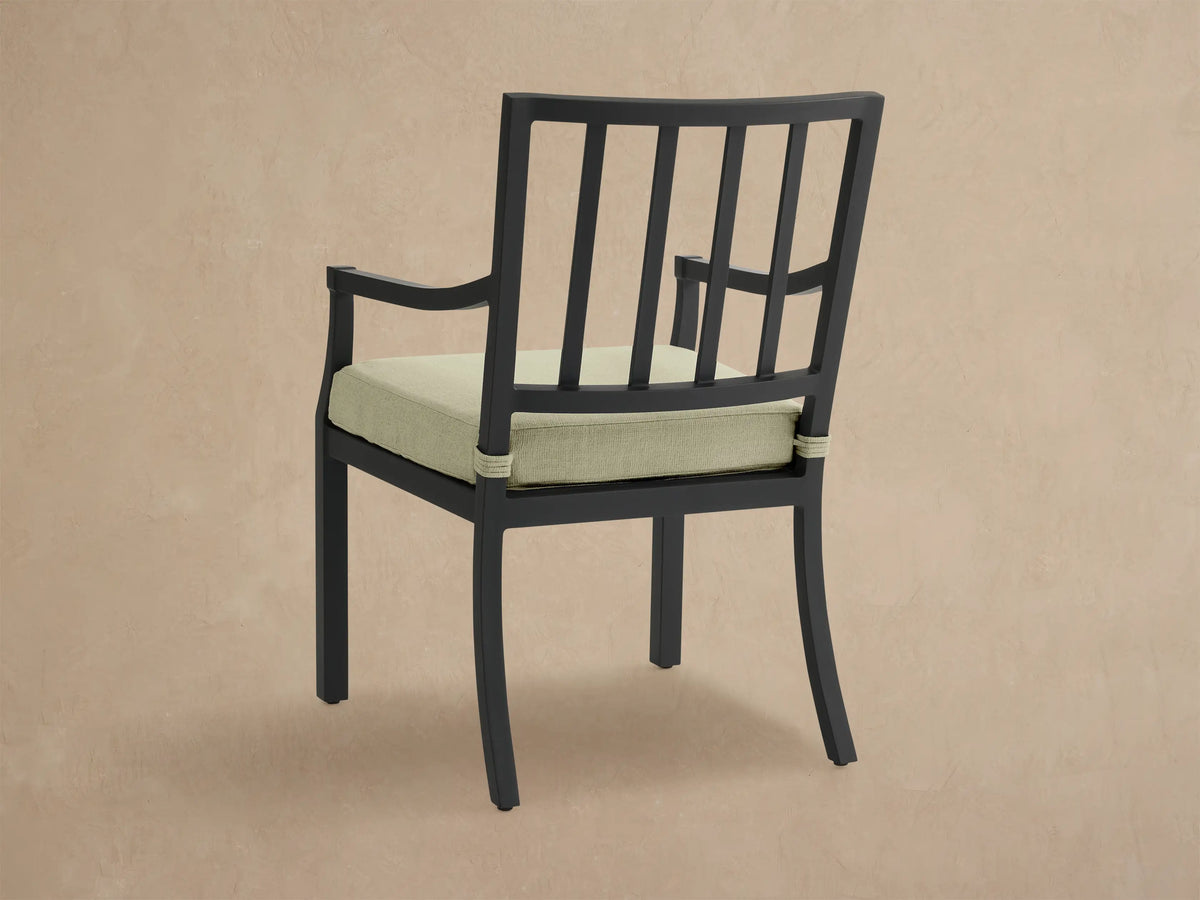 Close-up of Montego black aluminum dining arm chair with light green Eden Sage cushion, showing armrest and back.