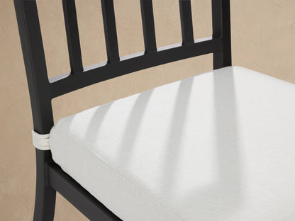 Dark gray aluminum Montego dining chair with light gray cushion, front view on patio against wood shingle wall.