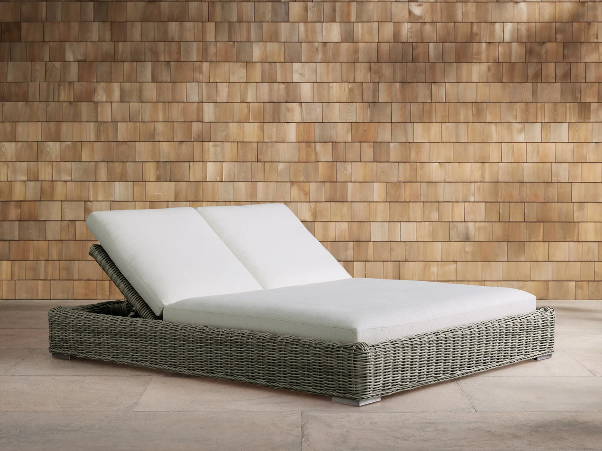 Light gray textured Montauk Outdoor Collection Cover on a rectangular outdoor furniture base, against a warm wooden shingle wall.