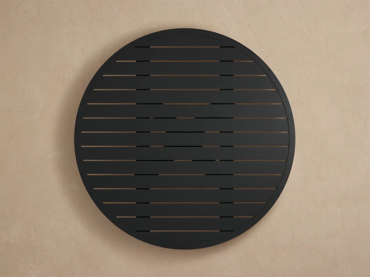 Close-up of Montego Outdoor Aluminum Round Dining Table, showing its dark gray, slatted top & smooth curved edge with textured finish.