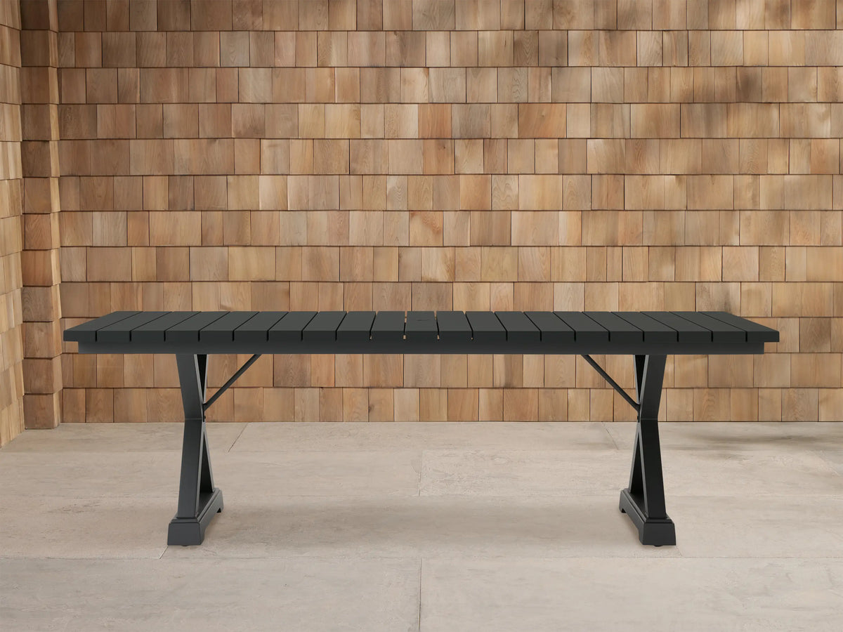 Dark gray Montego Outdoor Aluminum Dining Table with rectangular slatted top and A-frame legs, on a light patio.