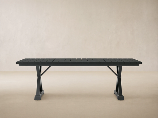 Dark gray Montego Outdoor Aluminum Dining Table with rectangular slatted top and A-frame legs, on a light patio.