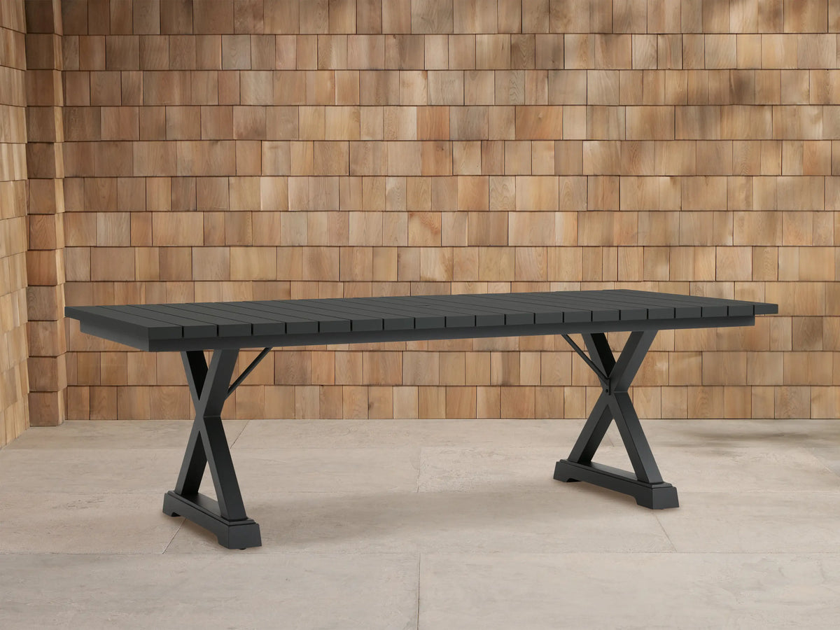 Dark gray Montego Outdoor Aluminum Dining Table with rectangular slatted top and A-frame legs, on a light patio.