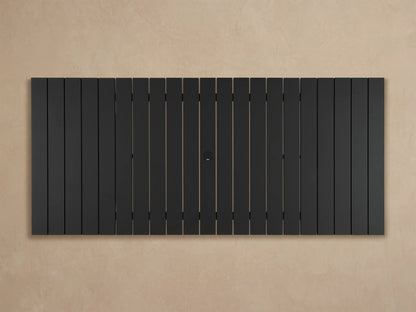 Close-up of Montego Outdoor Aluminum Dining Table. Dark gray slatted top and sturdy angled leg base on a light floor.