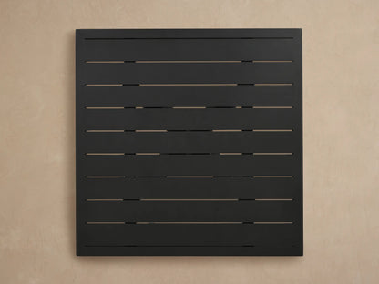 Montego Outdoor Aluminum Bar Table. Dark gray powder-coated slatted top and part of sturdy V-shaped aluminum base, angled.