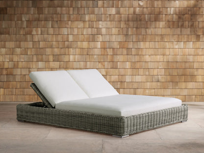 Side view of the Montauk Outdoor Double Chaise with light grey-green woven wicker and adjustable white cushions.