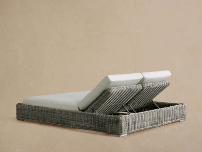 Rear-side view of a gray woven wicker Montauk Outdoor Double Chaise with two raised adjustable backrests and light gray cushions.