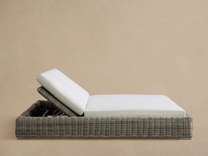 Side profile of the gray woven Montauk Outdoor Double Chaise with white cushions and stainless-steel feet. Backrest elevated.