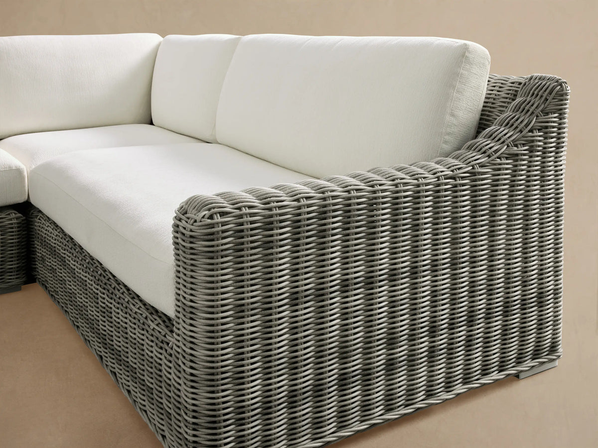 Montauk Outdoor Three-Piece Sectional with L-shaped gray woven resin wicker and white cushions on light patio tiles.