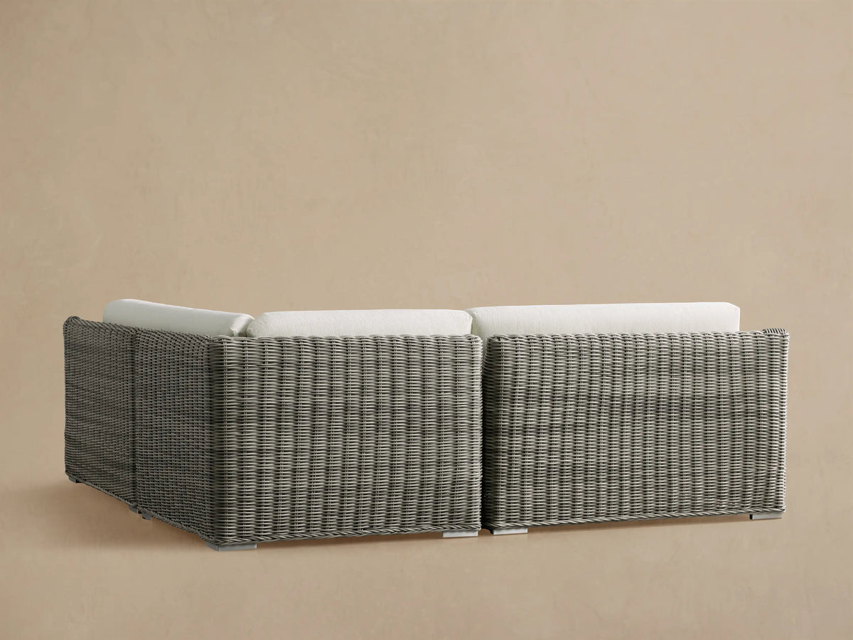 L-shaped Montauk Outdoor Sectional corner with textured light gray woven resin wicker frame and thick white cushions.