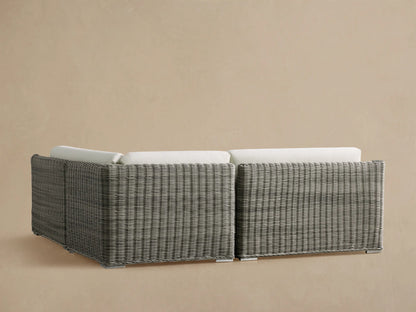 L-shaped Montauk Outdoor Sectional corner with textured light gray woven resin wicker frame and thick white cushions.