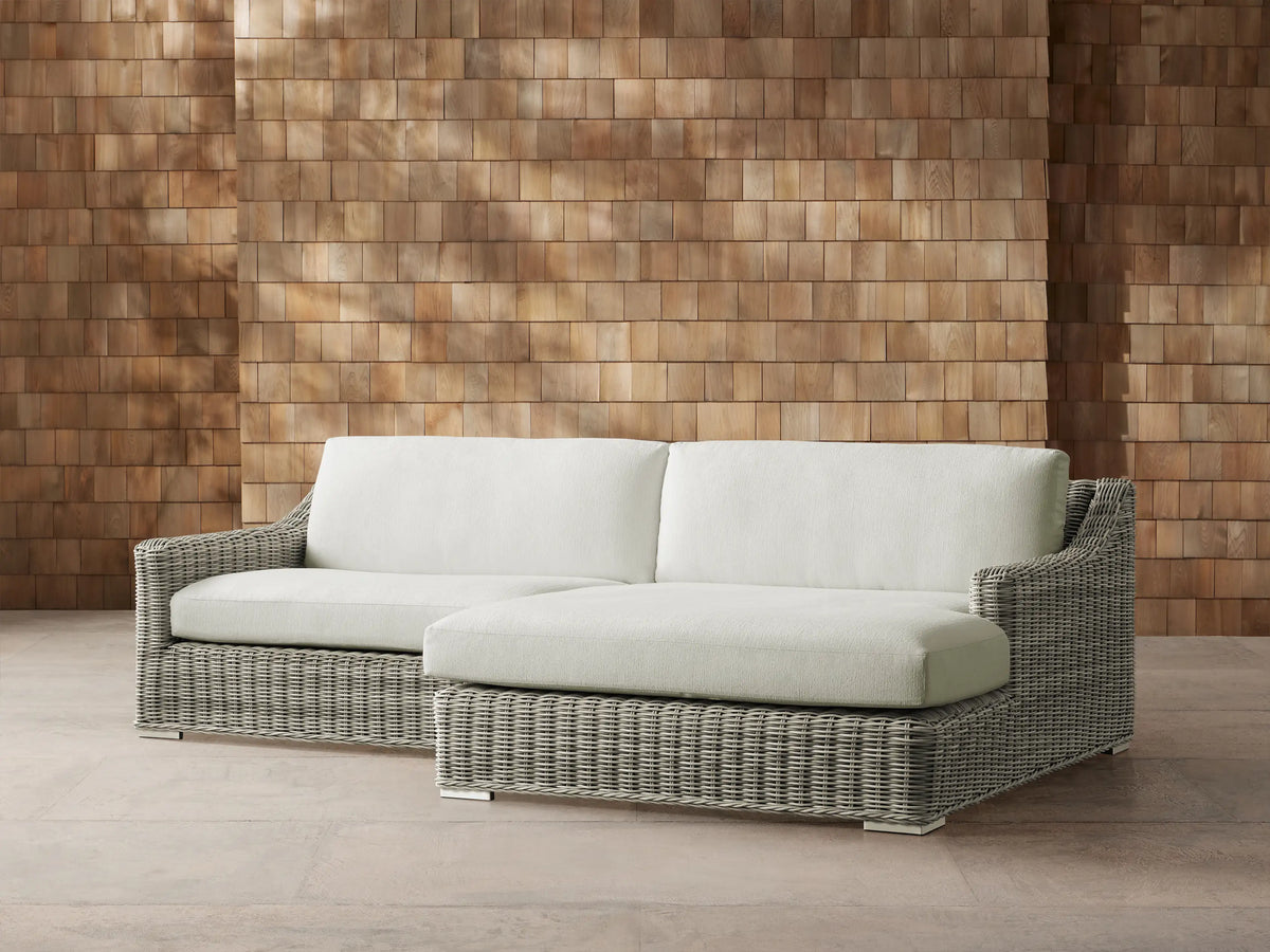 Montauk Outdoor Two-Piece Sectional with light gray woven resin wicker frame & pale green cushions against a wood wall.