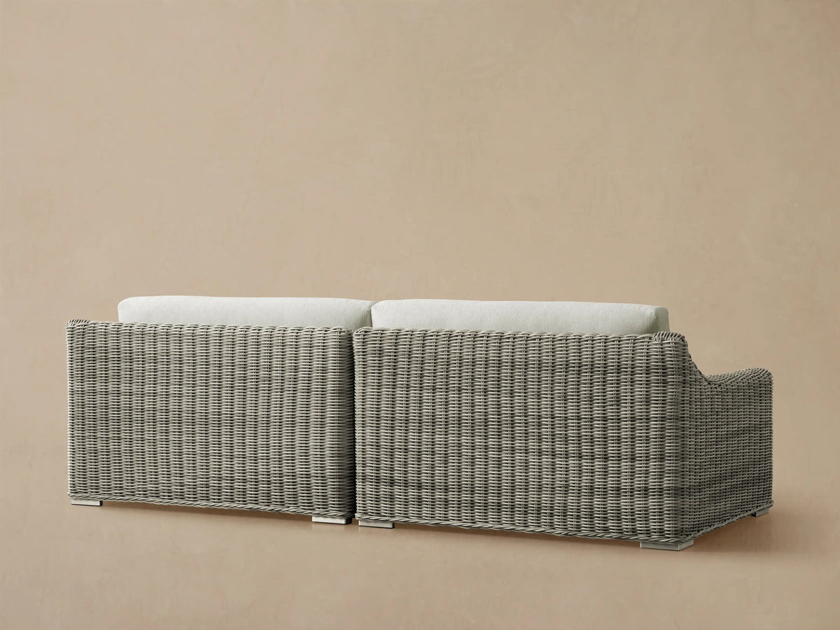 Close-up, angled view of Montauk Outdoor Two-Piece Sectional with gray handwoven resin wicker and cream seat and back cushions.