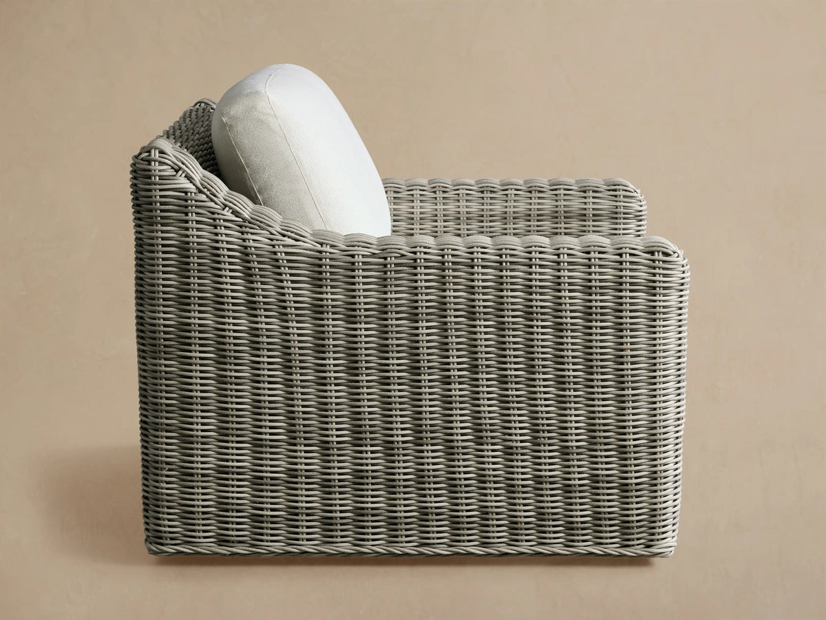 Rear view of the Vista Grey Montauk Outdoor Swivel Chair, featuring handwoven resin wicker and a white cushion.