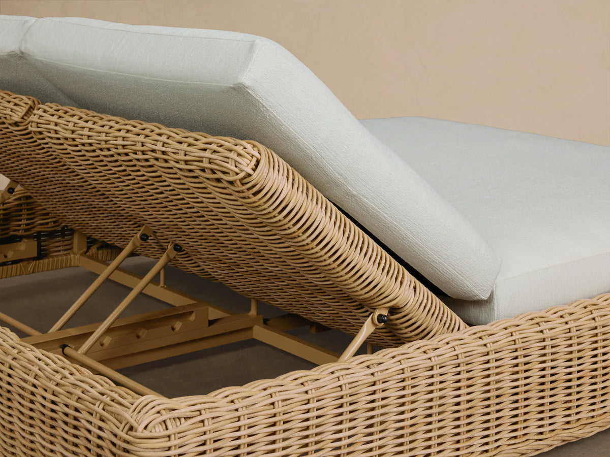 Side view of the light brown woven Montauk Outdoor Double Chaise with two white cushions and an inclined backrest.