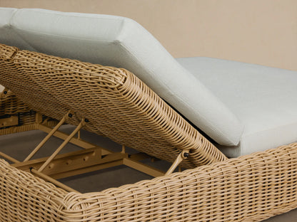 Side view of the light brown woven Montauk Outdoor Double Chaise with two white cushions and an inclined backrest.